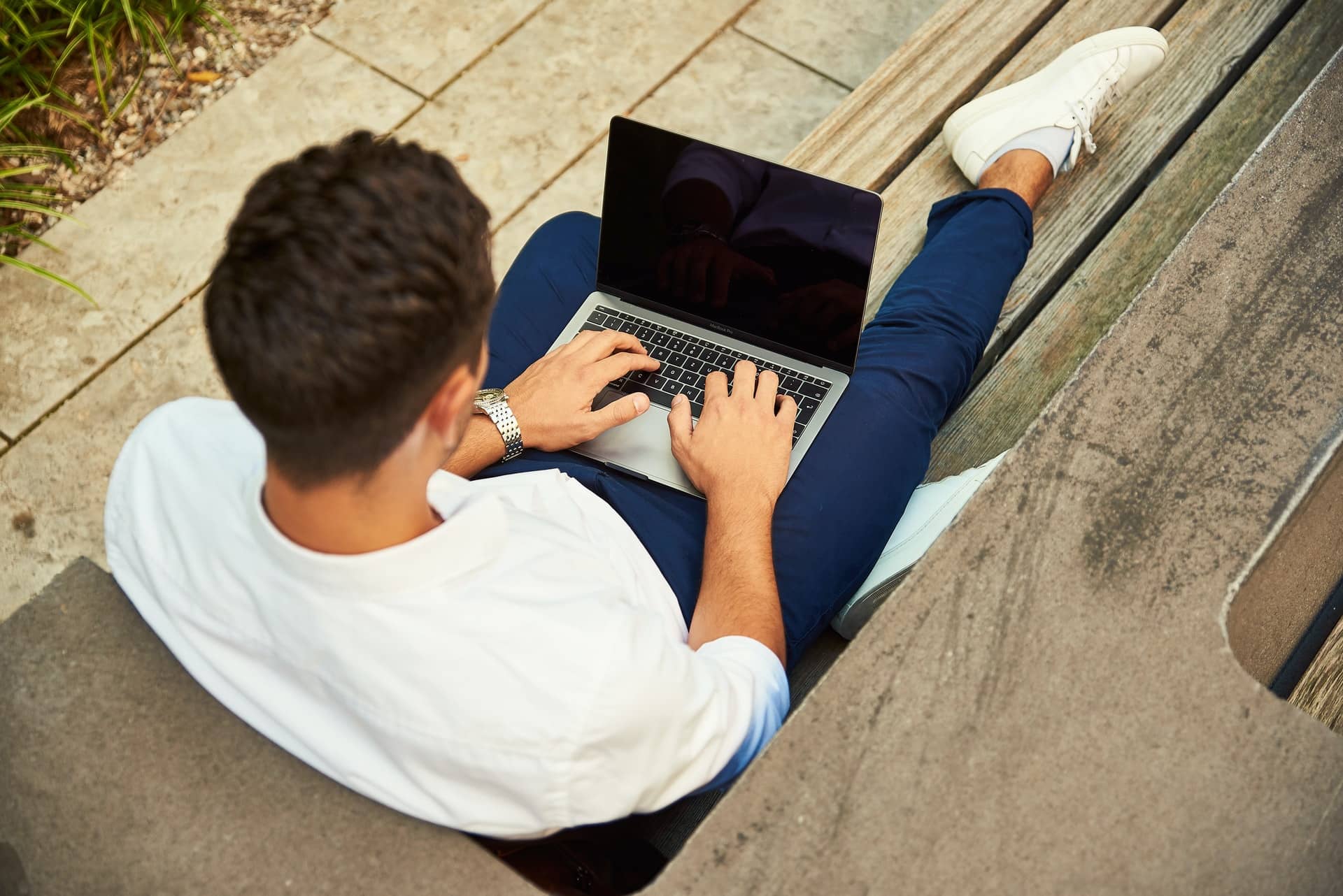 man sitting outside on bench with laptop